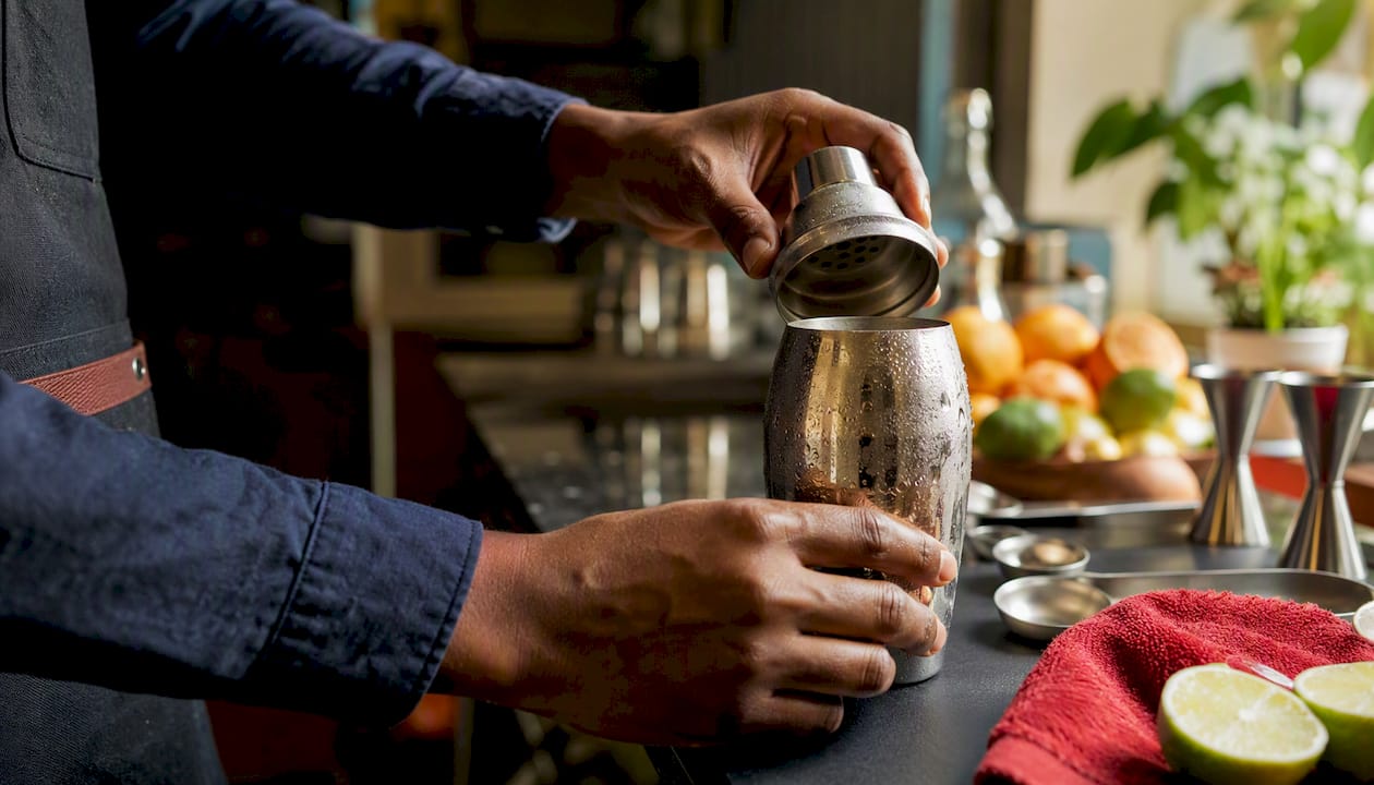 Hands opening cobbler shaker cap over bar counter